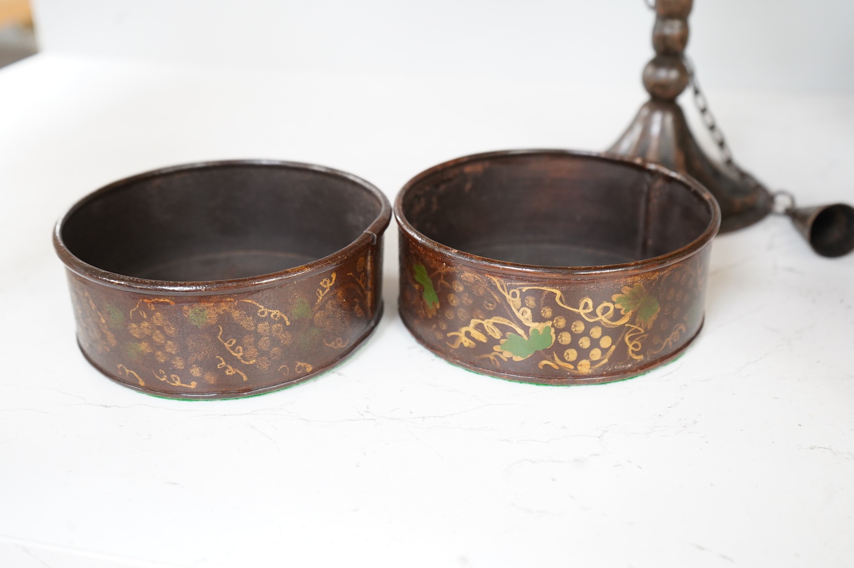 A pair of 19th century toleware wine coasters and an Arts & Crafts iron candlestick with attached snuffer, 21cm high
